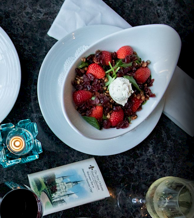 A restaurant scene with a chef in whites beside plates of burgers, fries, steak, and berry desserts.